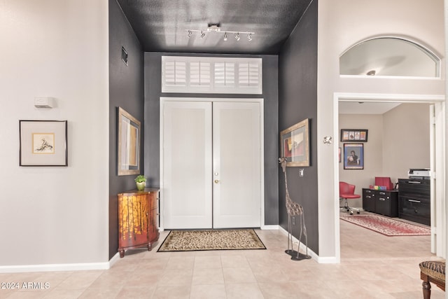 tiled entryway featuring french doors and track lighting