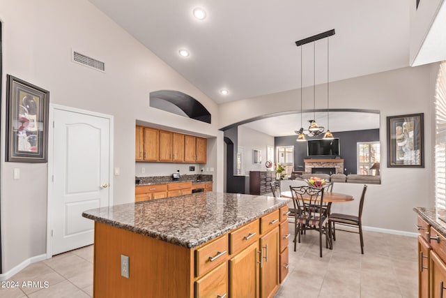 kitchen featuring a fireplace, a kitchen island, hanging light fixtures, and vaulted ceiling