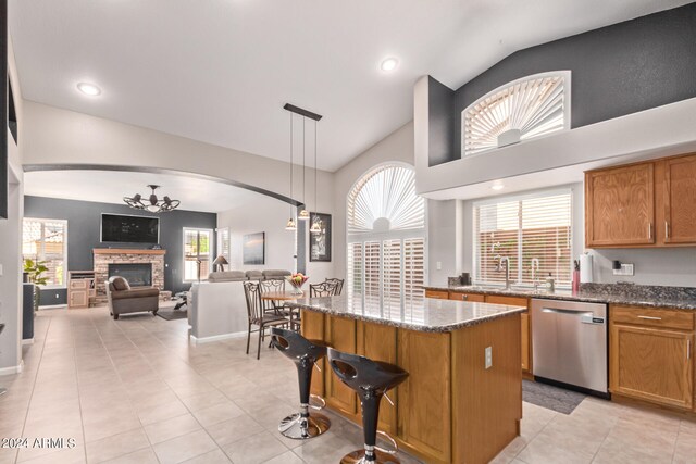 kitchen with dishwasher, lofted ceiling, dark stone counters, decorative light fixtures, and a kitchen island