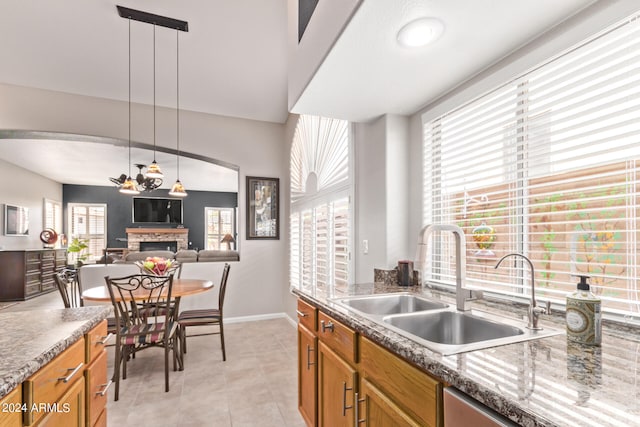 kitchen featuring plenty of natural light, a stone fireplace, sink, and hanging light fixtures