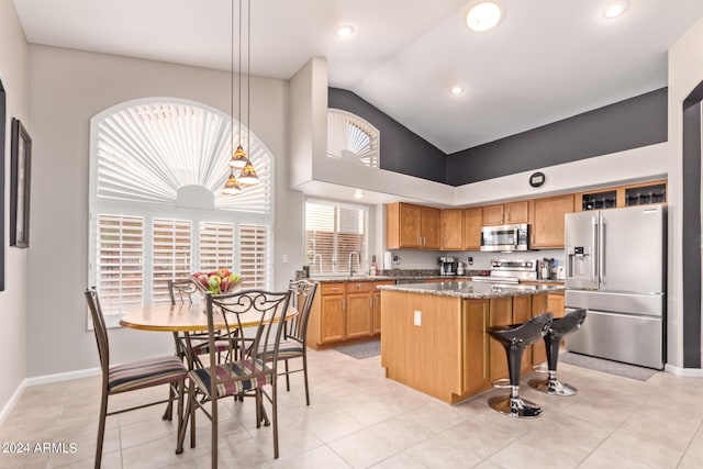 kitchen featuring a center island, stainless steel appliances, a wealth of natural light, and dark stone counters