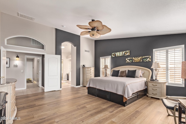 bedroom featuring ensuite bath, light hardwood / wood-style flooring, vaulted ceiling, and ceiling fan