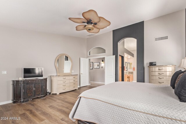 bedroom with ceiling fan, ensuite bathroom, and wood-type flooring