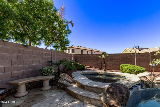 view of patio / terrace featuring an in ground hot tub and pool water feature