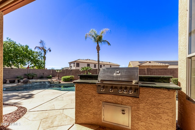 view of patio with area for grilling, a grill, and a fenced in pool