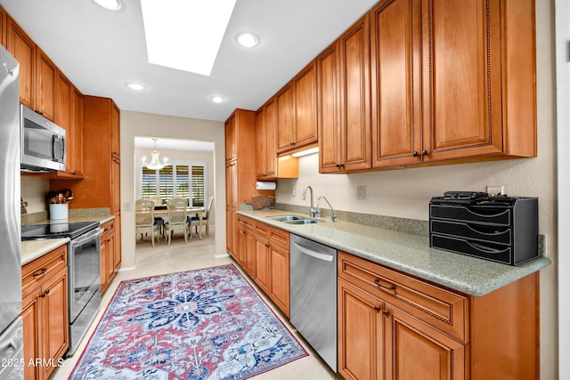 kitchen with sink, light tile patterned floors, appliances with stainless steel finishes, a skylight, and a notable chandelier