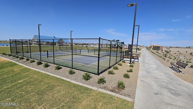 view of tennis court featuring a lawn and fence