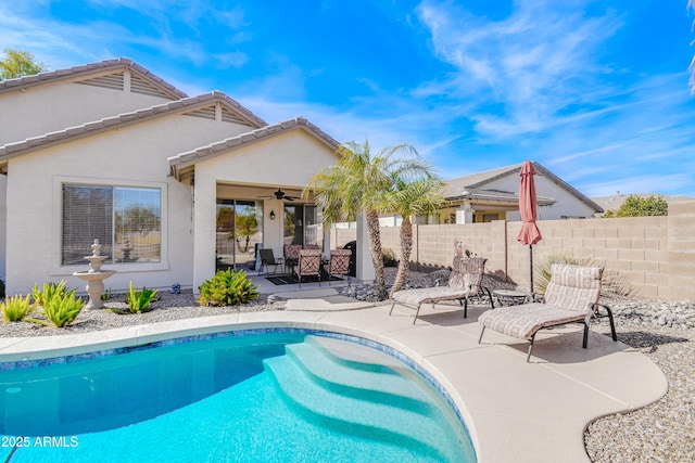 back of property featuring a fenced in pool, ceiling fan, and a patio area