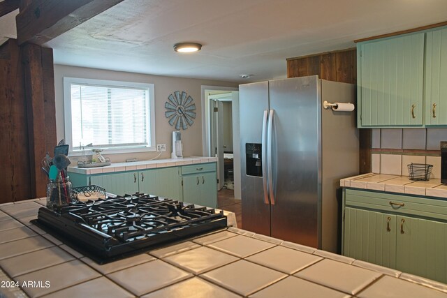 kitchen featuring kitchen peninsula, light tile patterned floors, stainless steel refrigerator with ice dispenser, green cabinets, and ceiling fan