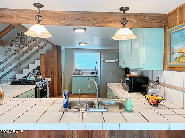 kitchen featuring pendant lighting, tile counters, sink, and stainless steel appliances