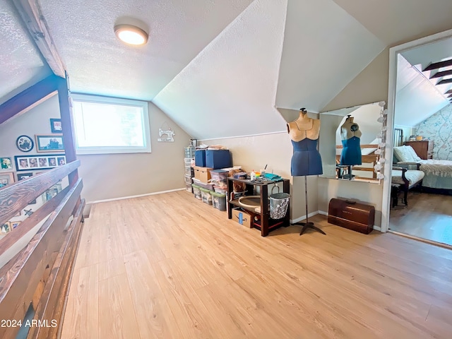 bonus room with light hardwood / wood-style flooring, a textured ceiling, and vaulted ceiling