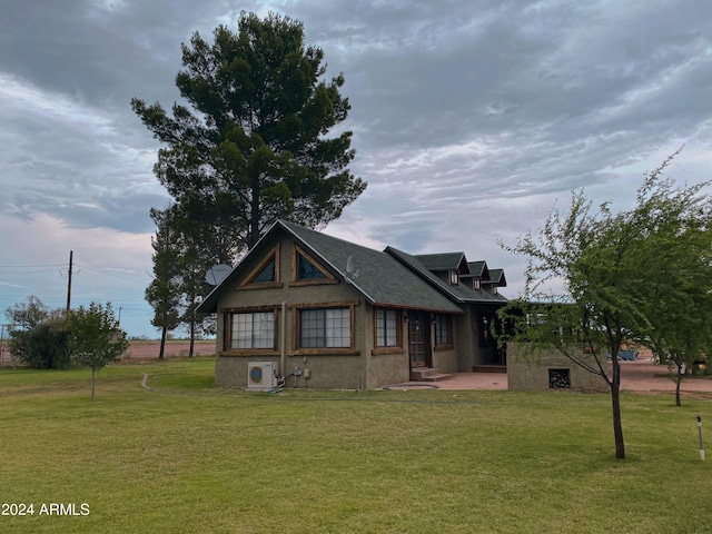 view of front facade with stucco siding, a front yard, and ac unit