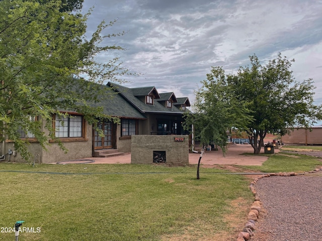 view of front of property with stucco siding, roof with shingles, and a front lawn