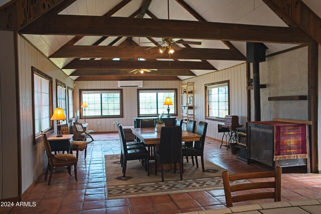 dining room featuring a wood stove, an AC wall unit, lofted ceiling with beams, and light tile patterned floors