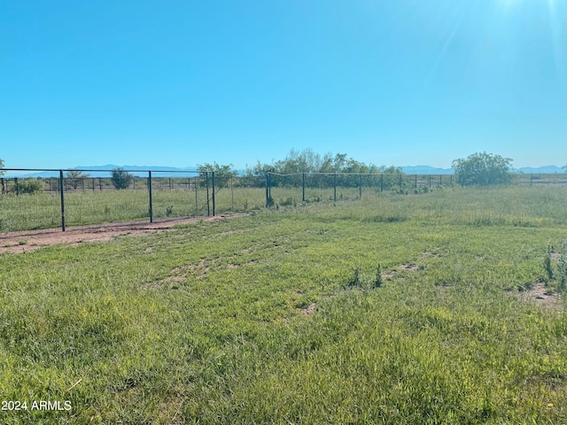 view of yard with a rural view, a mountain view, and fence