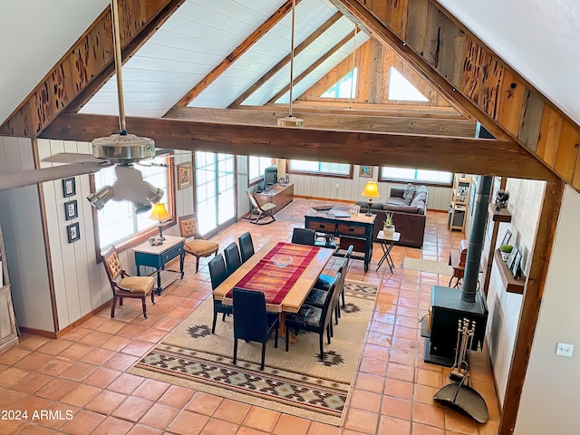 tiled dining room with a wood stove, high vaulted ceiling, and beam ceiling