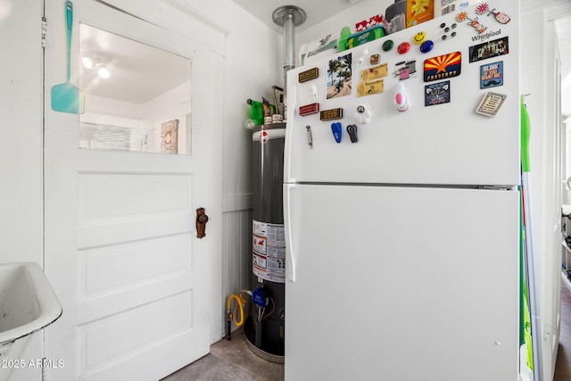 interior space with concrete floors, gas water heater, a sink, and freestanding refrigerator