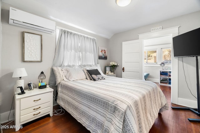 bedroom with a wall unit AC, dark wood-style floors, and baseboards