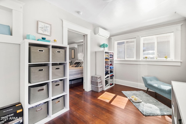 interior space featuring wood-type flooring, baseboards, and a wall mounted AC