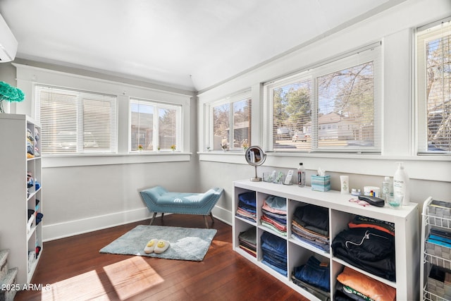 living area with baseboards, wood finished floors, and a wall mounted AC