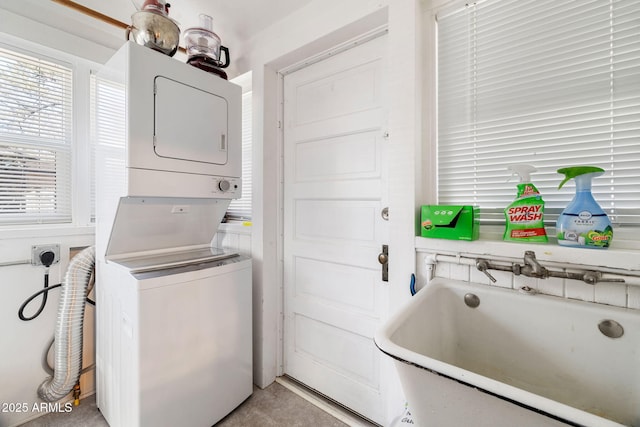 washroom with laundry area, a sink, and stacked washer and clothes dryer