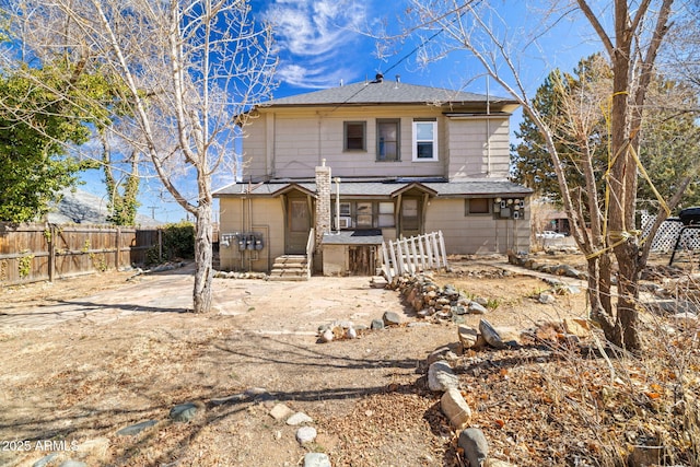 back of property with a shingled roof and fence