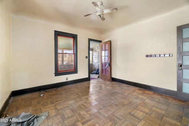 empty room with a ceiling fan and baseboards