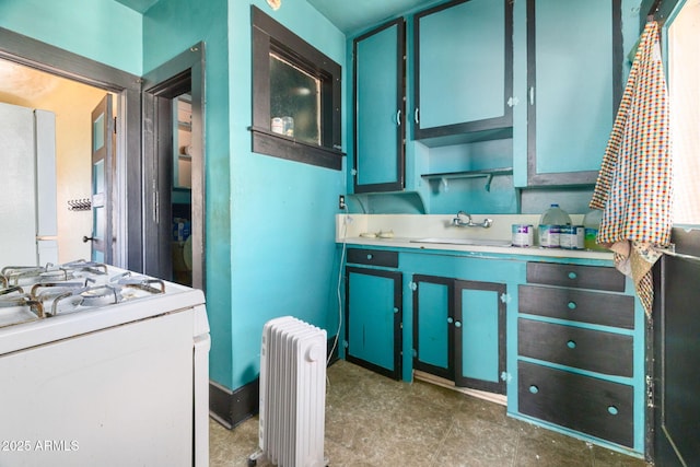 kitchen featuring radiator, light countertops, a sink, and white range with gas stovetop
