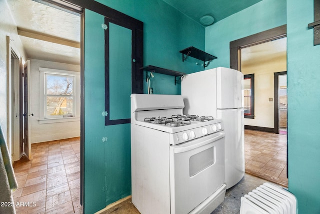 kitchen with radiator, white range with gas cooktop, and baseboards