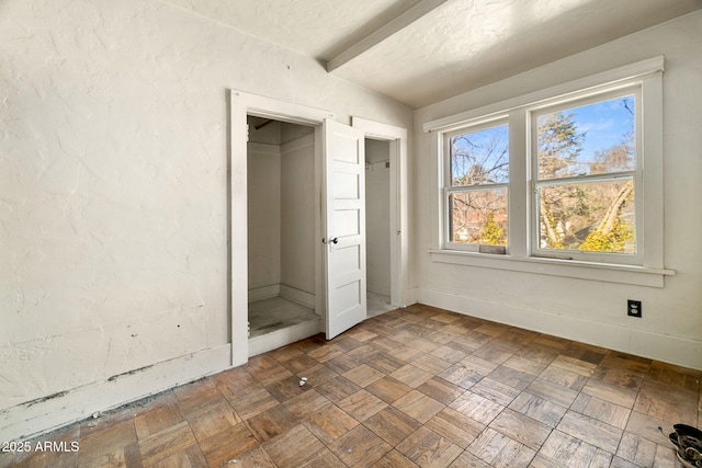 unfurnished bedroom with lofted ceiling with beams and baseboards
