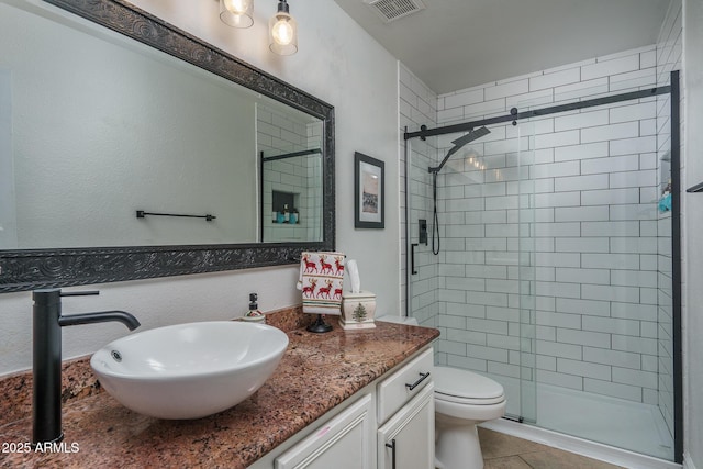 bathroom featuring toilet, a stall shower, visible vents, and vanity