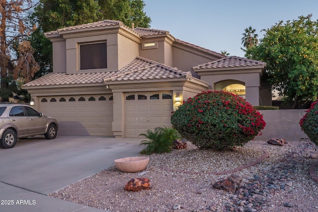 mediterranean / spanish-style house featuring driveway, a tiled roof, an attached garage, and stucco siding