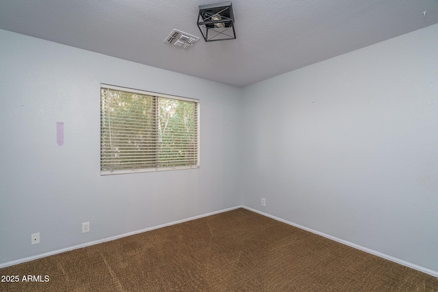 empty room featuring baseboards, visible vents, and dark carpet