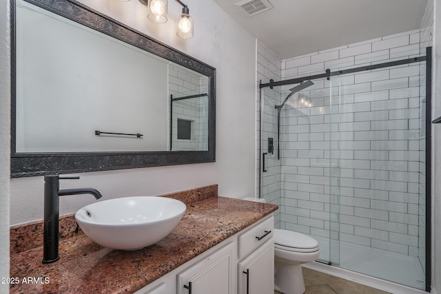 full bath featuring toilet, vanity, visible vents, a shower stall, and tile patterned floors