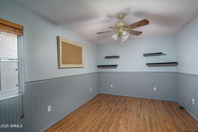 unfurnished room featuring wainscoting, ceiling fan, and wood finished floors