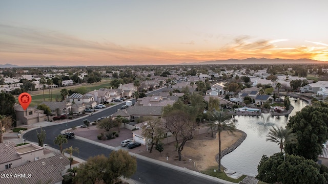 aerial view at dusk featuring a residential view and a water and mountain view