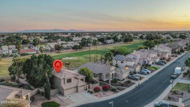 aerial view at dusk with view of golf course and a residential view