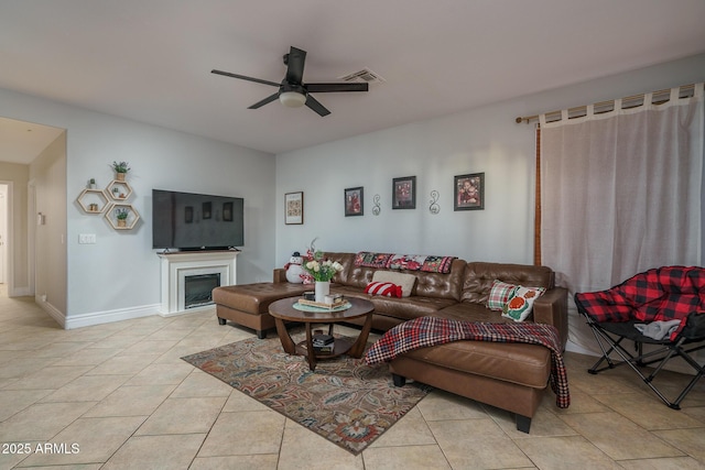 living area featuring a fireplace, visible vents, ceiling fan, tile patterned flooring, and baseboards