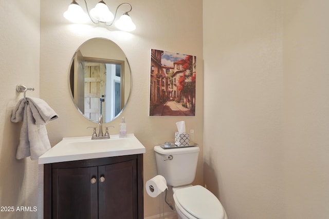 bathroom with toilet, an inviting chandelier, and vanity
