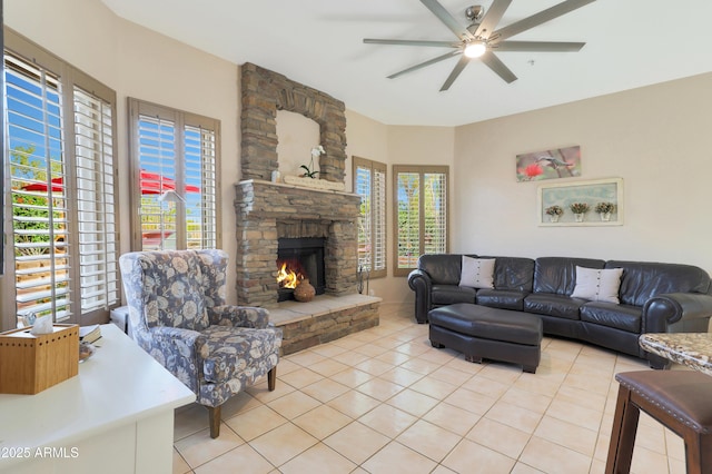 living room featuring light tile patterned floors, a stone fireplace, a ceiling fan, and plenty of natural light
