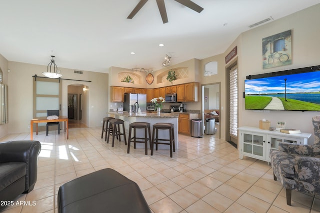 living room featuring arched walkways, light tile patterned flooring, a ceiling fan, and visible vents
