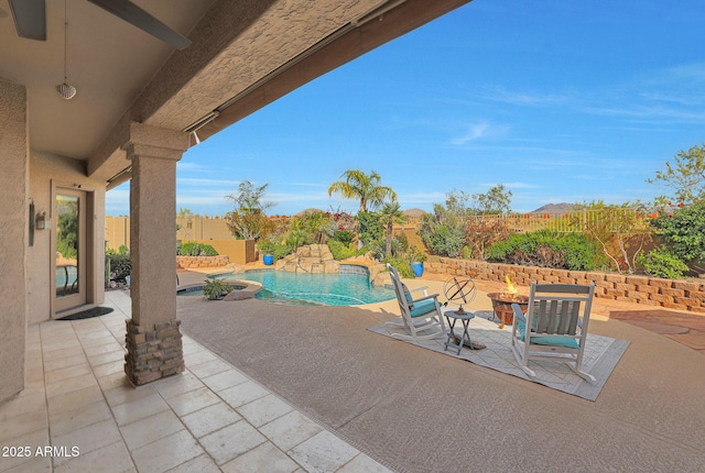 view of patio / terrace with a pool with connected hot tub, a fenced backyard, and an outdoor fire pit