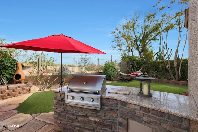 view of patio with area for grilling, a fenced backyard, and exterior kitchen