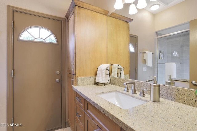 bathroom with a shower stall, vanity, and an inviting chandelier