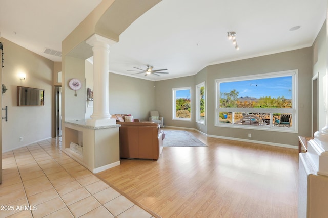 living area featuring ornamental molding, decorative columns, and a ceiling fan