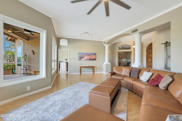 living area with baseboards, a ceiling fan, visible vents, decorative columns, and wood finished floors