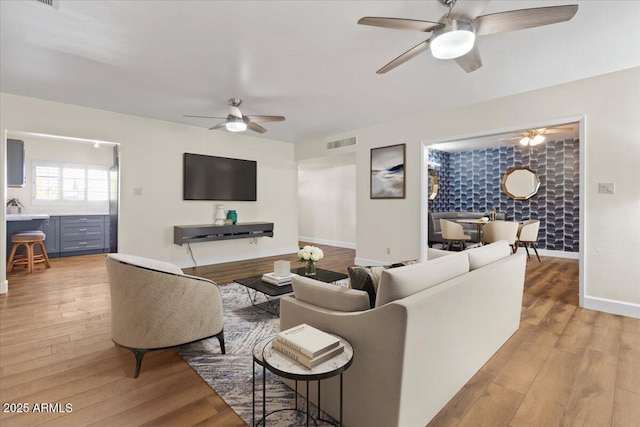 living room with light hardwood / wood-style flooring and ceiling fan