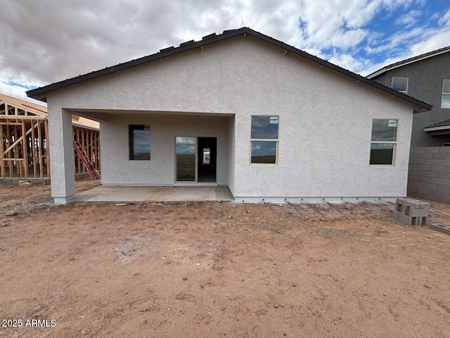 back of property with stucco siding and a patio