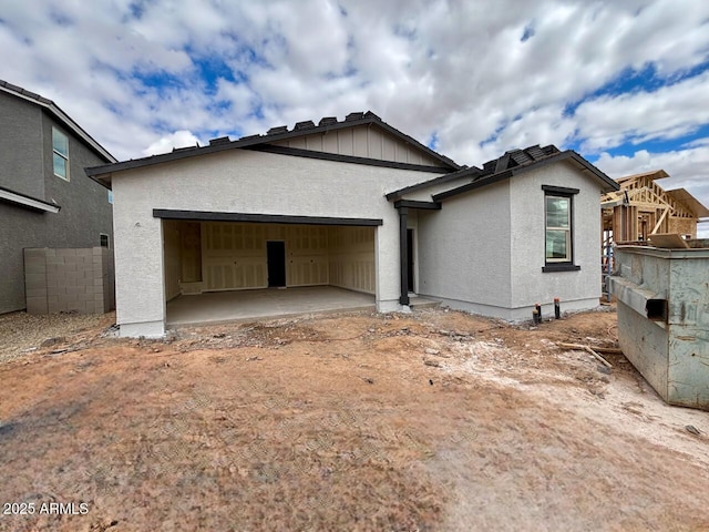 view of front facade featuring stucco siding, a patio, a garage, and fence