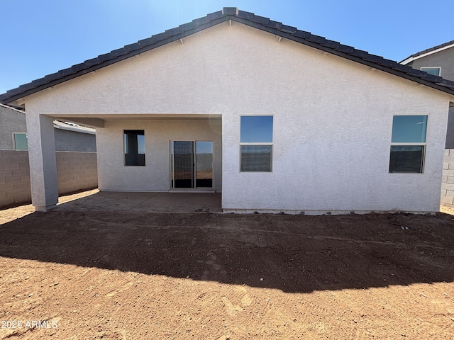 rear view of house featuring fence, a patio, and stucco siding
